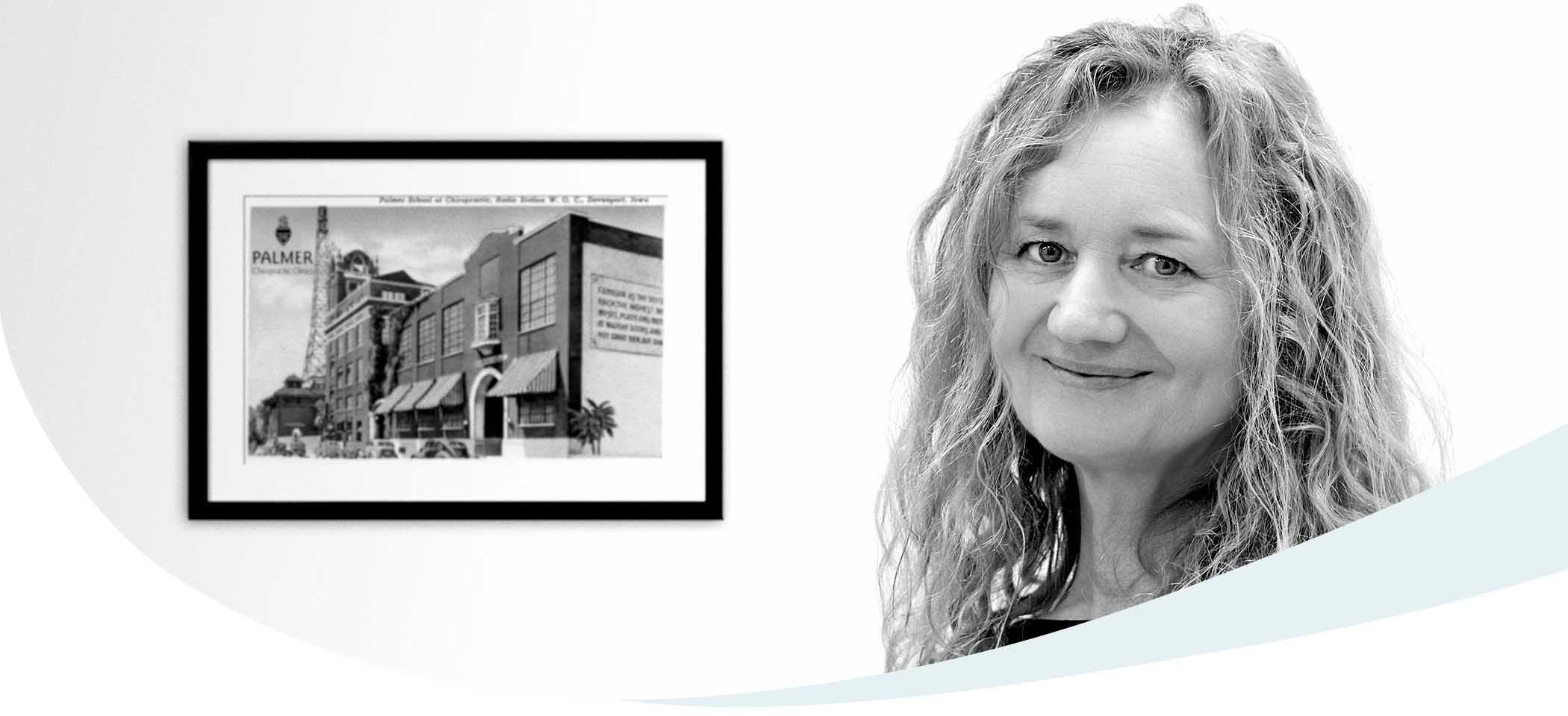 Dr. Irmgard Verderber in ihrer Ordination vor einer Abbildung des Palmer College of Chiropractic, an dem sie ihre chiropraktische Ausbildung absolvierte.